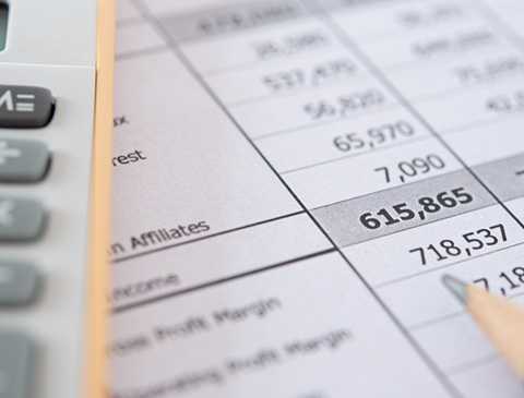 A close-up image of a calculator, a balance sheet and a tip of a pencil.